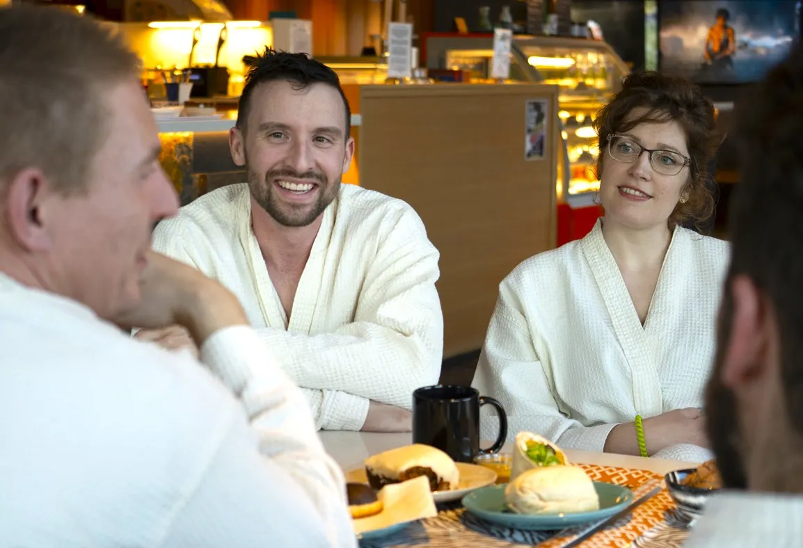 several people wearing robes having a conversation while eating